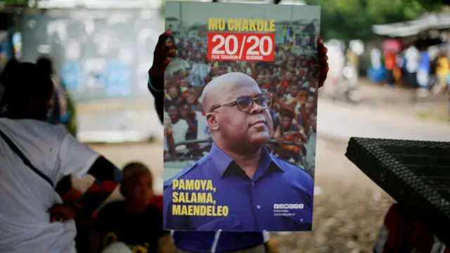 A supporter of holds a portrait of president Felix Tshisekedi of Union for Democracy and Social Progress (UDPS) as they prepare to celebrate ahead of the announcement of provisional results of the December presidential election, at their party's headquarters in Kinshasa, Democratic Republic of Congo December 31, 2023