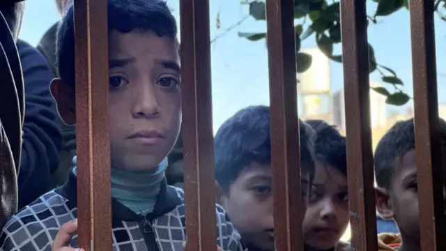 Palestinian children at the gates of a mortuary in Khan Younis