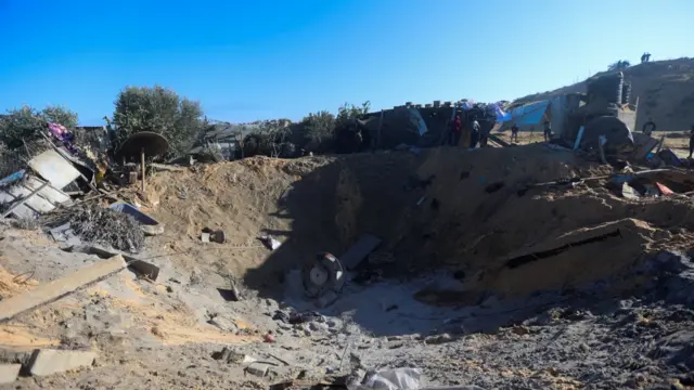 Palestinians inspect a crater in al-Mawasi