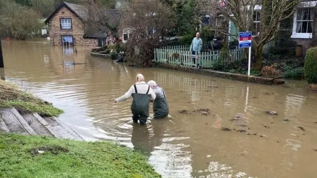 Mario Thomas and his wife Lisa wading through flood water on their way to The Boat Inn pub