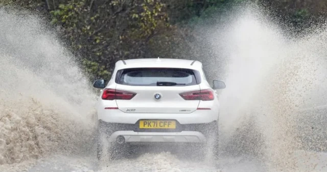 File photo of a car going through a puddle spraying rainwater