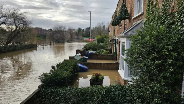 A street showing the road and front gardens flooded