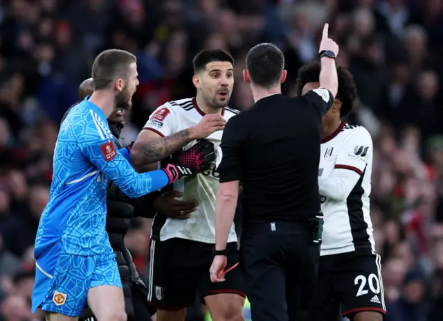 Fulham players accost referee Kavanagh after a disagreeable decision.