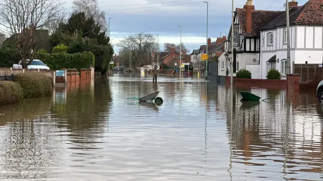 Wheelbarrows submerged in floodwater in Longford, Gloucestershire