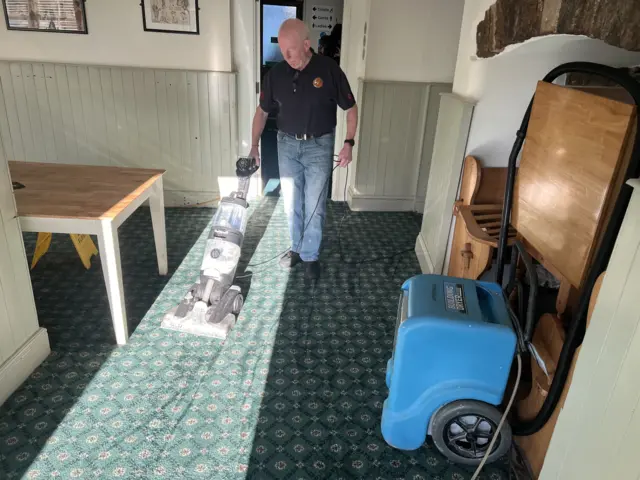 Man hoovering pub after flood