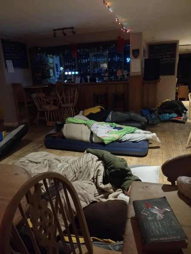 People sleeping on the pub floor, near the bar