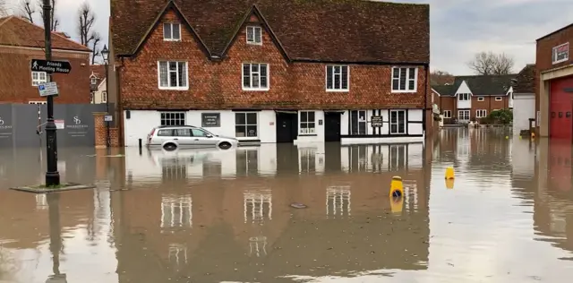 Flooding outside a pub in Marlborough with a car stuck outside it