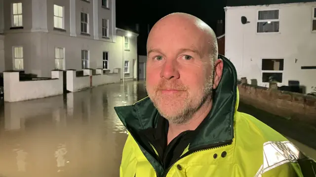 Nick Green in a high-vis jacket in front of flood water