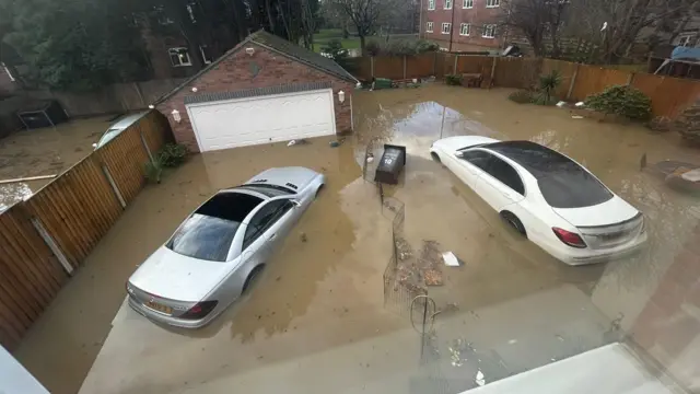 Two cars and a garage submerged in flood water