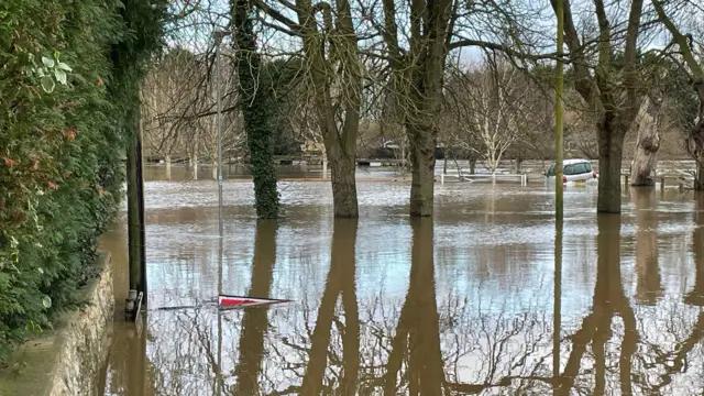 A flood sign floats on flood water.