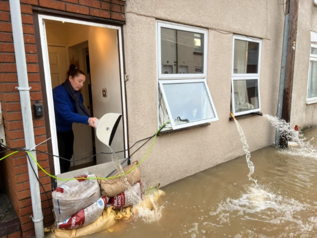 Woman empties water out of her home in Alney Island, Gloucestershire