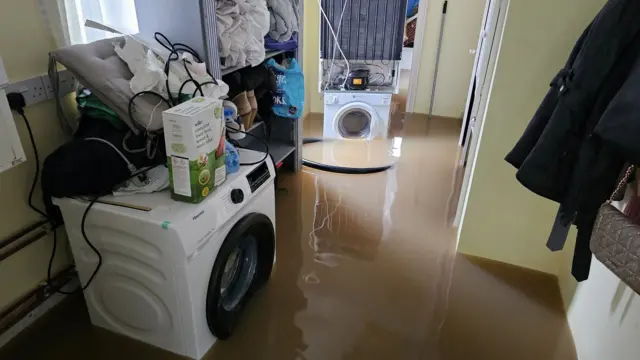 A utility room flooded with brown water around two washing machines