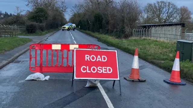 Road Closed sign with a police car in the background