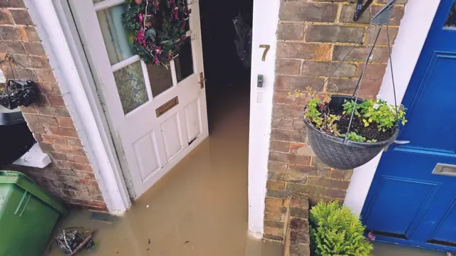 A white front door open with flood water into the house