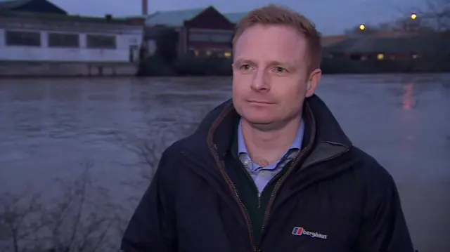 Robbie Moore MP stands next to a river in Nottinghamshire