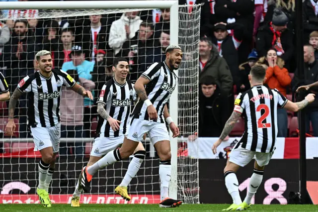 Joelinton celebrates with teammates after his cross is deflected in