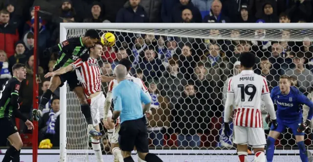 Joao Pedro leaps above a Stoke City player to score