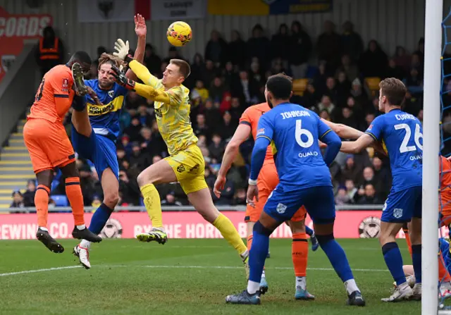 Axel Tuanzebe heads the ball into the net while under pressure from Wi,bledon players