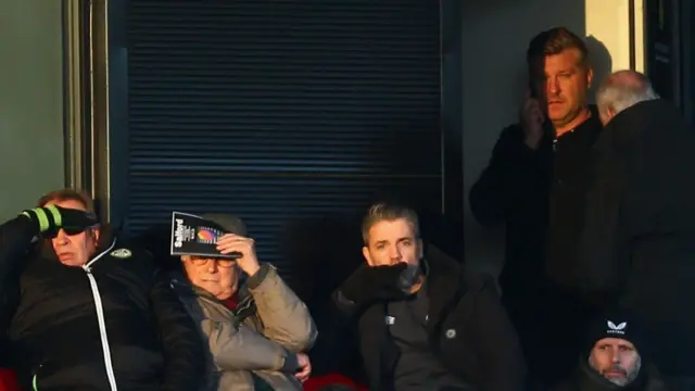 Salford boss Karl Robinson (standing right) takes his place in the stands after being sent off against Forest Green