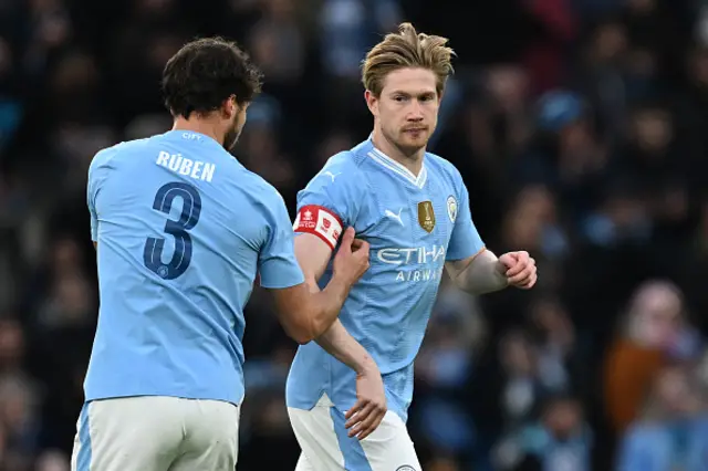 Ruben Dias passes the captain's armband to Manchester City's Belgian midfielder Kevin De Bruyne