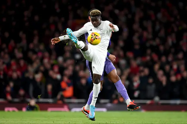 Bukayo Saka of Arsenal and Joe Gomez of Liverpool (obscured) battle for possession