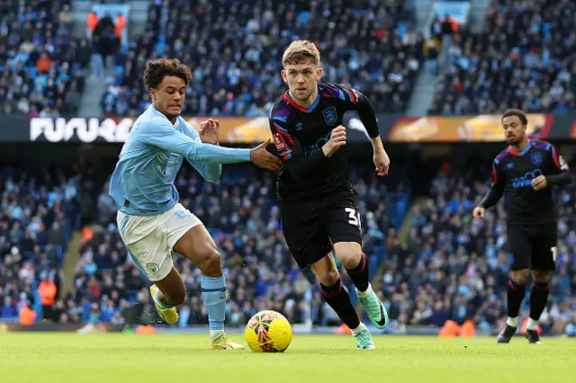 Ben Jackson of Huddersfield Town runs with the ball whilst under pressure from Oscar Bobb