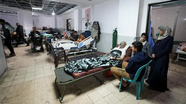 Palestinians wounded lie on beds as displaced people shelter at Shuhada al-Aqsa Hospital.