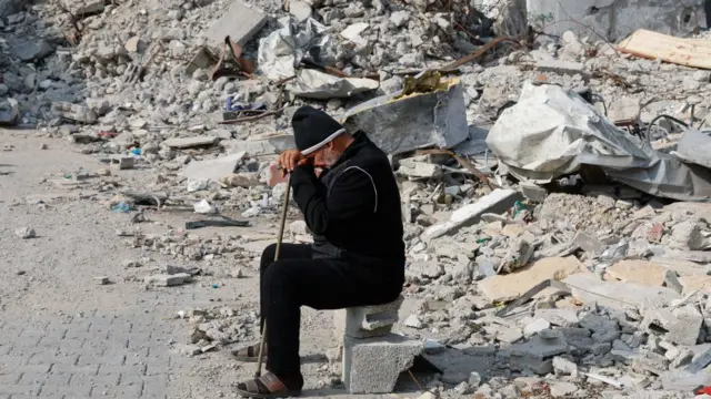 A Palestinian man on concrete blocks amongst rubble of a house in Rafah