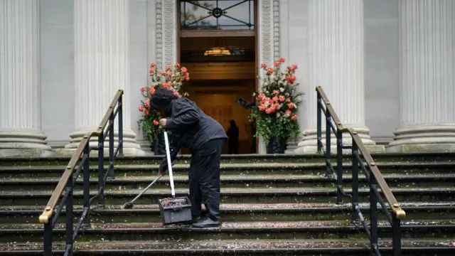 Lady sweeping confetti from outside Old Marylebone Town Hall on day of 100 weddings