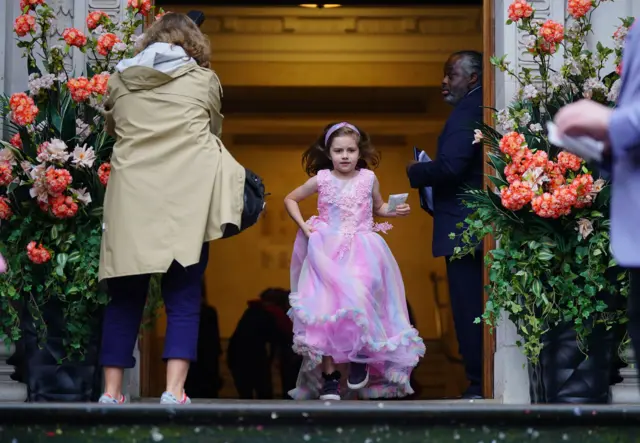 A young wedding guest runs to grab her spot to throw confetti