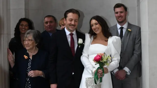 A bride and groom smile as they pose for a picture