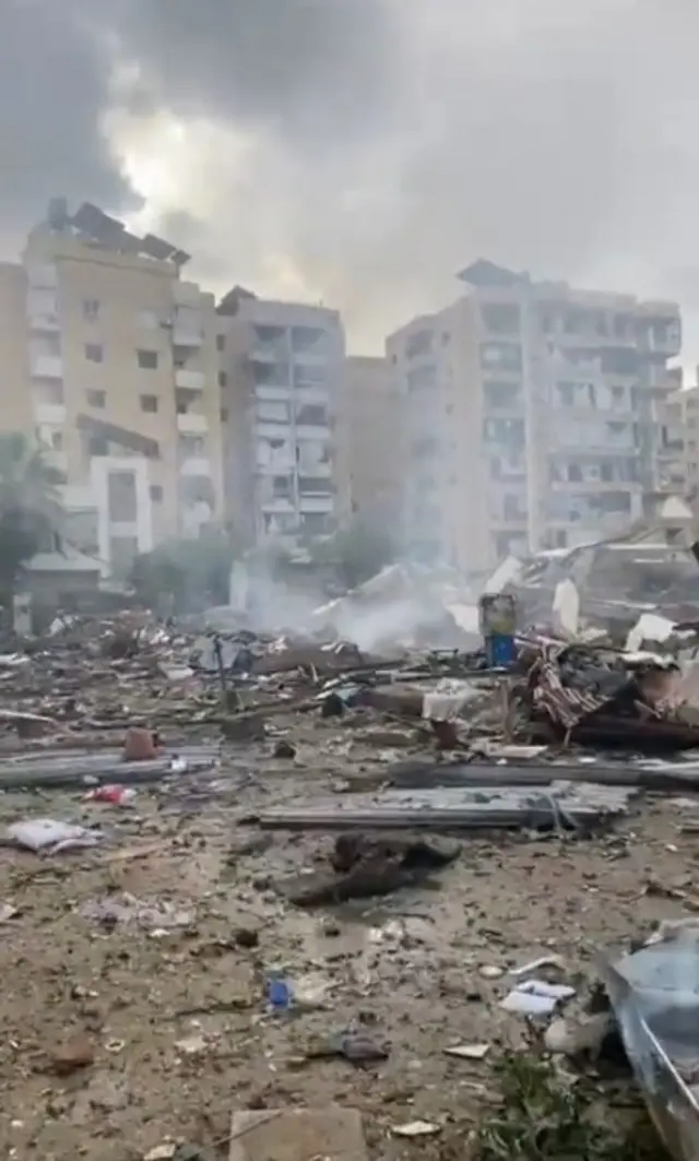 Debris amid high-rise buildings, with visible damage in the scene