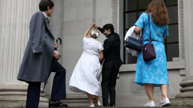 A newlywed couple share a dance on the steps of town hall.