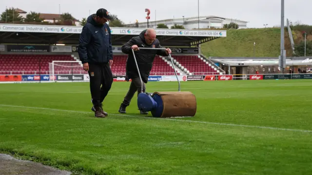 Groundsmen soak up water on the field at Northampton