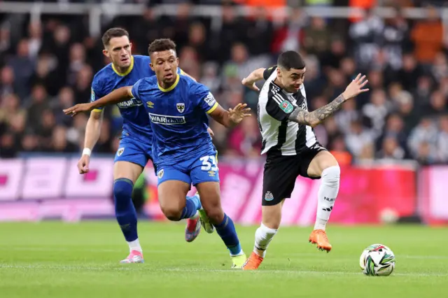 Miguel Almiron is challenged by Isaac Ogundere