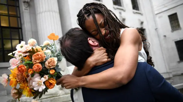 Natasha Whitter embraces Connor Lynch while holding a bouquet of flowers outside Marylebone Town Hall