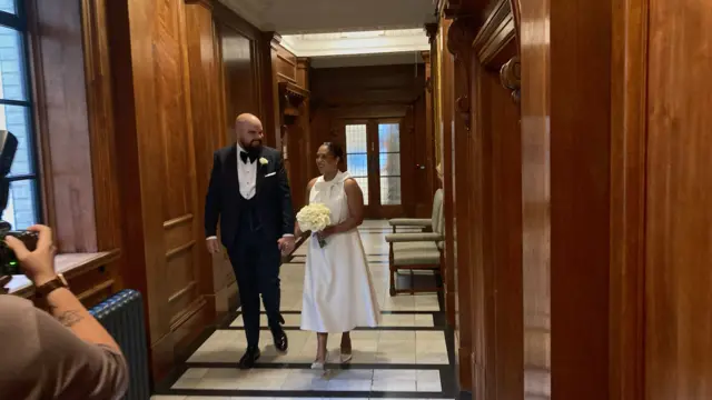 The bride and groom walk down the hallway