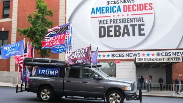 A grey pick-up truck, decorated with Trump and Vance flags, drives by CBS's New York headquarters