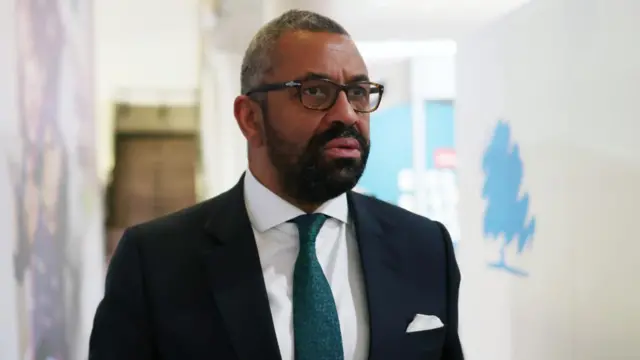 James Cleverly at Tory conference. The Conservative Party's logo of a blue tree graphic is visible in the background.