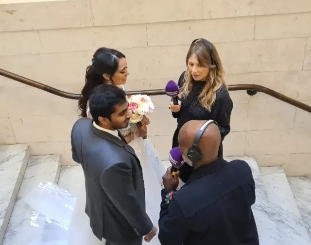 Eddie Nestor and Wendy Hurrell interviewing a couple after their wedding ceremony