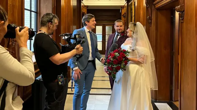 Nicky speaking to the couple, with BBC cameras filming them