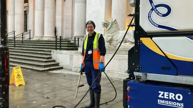 A cleaner in a hi-vis jacket smiles outside Old Marylebone Town Hall