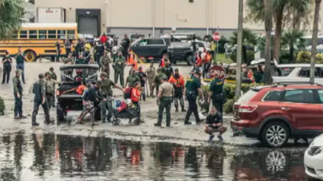 Uniformed individuals assemble in a flooded region of Pinellas.