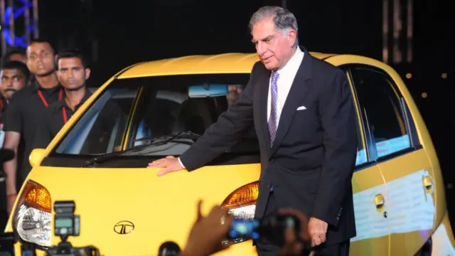 Ratan Tata poses next to a Nano car during its launch in Mumbai in 2009