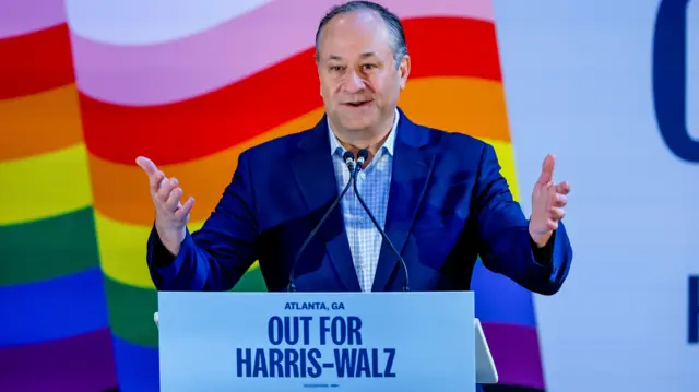 Second Gentleman Doug Emhoff stands in front of a pride flag and addresses a crowd in Georgia