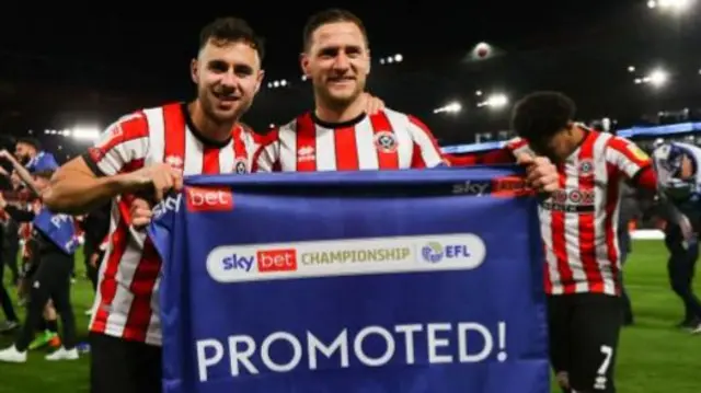 George Baldock and Billy Sharp holding a banner as Sheffield United celebrate winning promotion to the Premier League