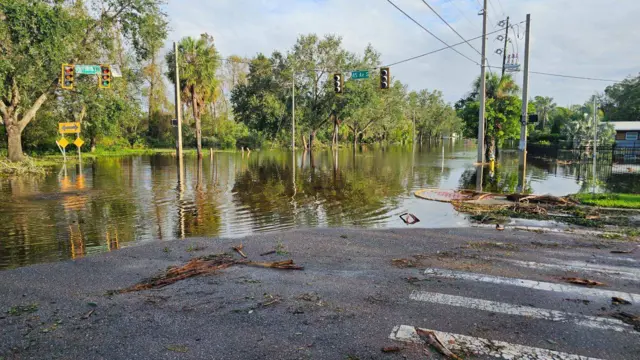 View of flooded street with mug, dirt and debris covering drier parts of pavement