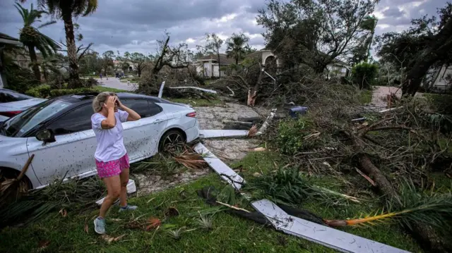 A woman reacts to the damage to her home after a tornado formed by Hurricane Milton touched down