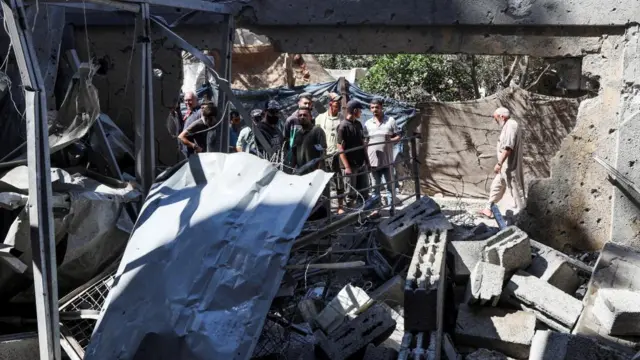 Palestinians inspect the site of an Israeli strike on a school sheltering displaced people
