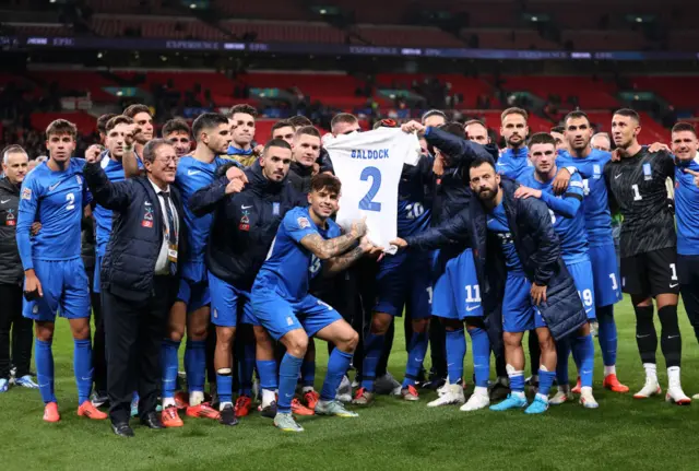 Greece players holding Baldock shirt